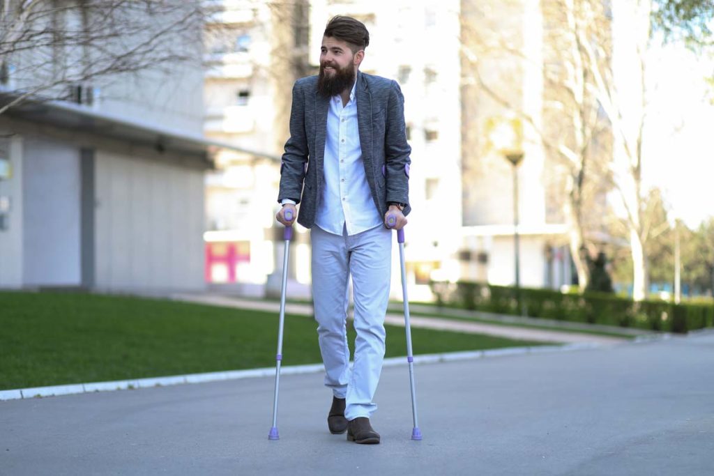 Young disabled man walking outside with assistive cane