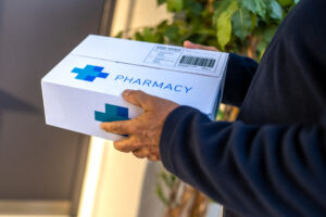 Hands holding cardboard box with pharmacy medications order close up
